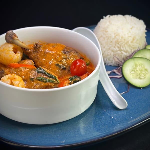 Red curry with duck, shrimp, lychee, and cherry tomatoes, served with rice and cucumber.